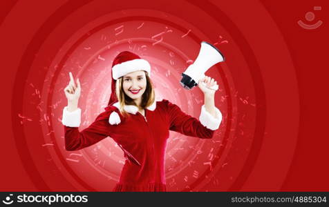 Christmas is coming. Young attractive Santa girl screaming in megaphone