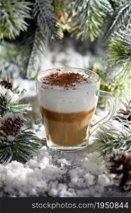 Christmas latte macchiato. A great hot coffee drink with chocolate shavings, among the snow-covered pine branches and snow.