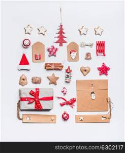 Christmas layout with craft paper wrapping gift boxes, tags, cookies, red holiday decoration, present, spices, Santa hat and red Christmas tree on white desk background, top view, flat lay.