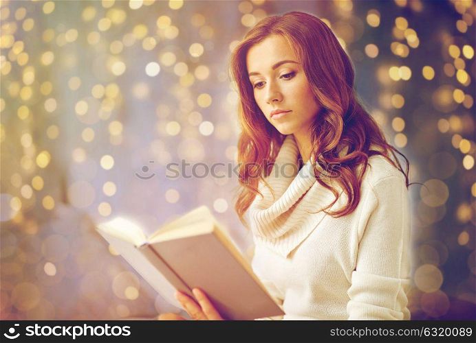 christmas, leisure and people concept - young woman reading book at home. young woman reading book at home