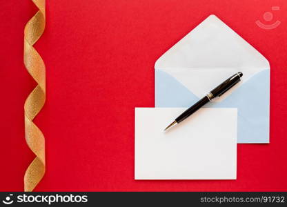 Christmas letter and pen over a red background with golden ribbon. Christmas letter over a red background