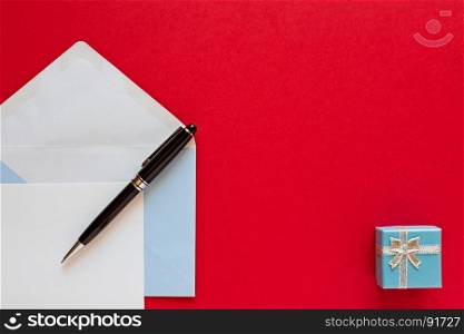 Christmas letter and pen over a red background with present. Christmas letter over a red background