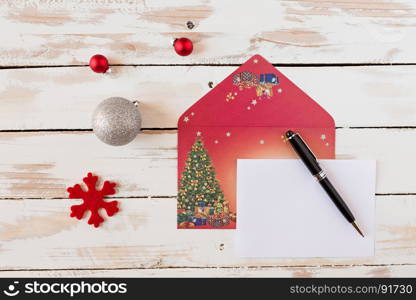 Christmas letter and pen over a rustic wooden table with decorations. Christmas letter over a rustic wooden table