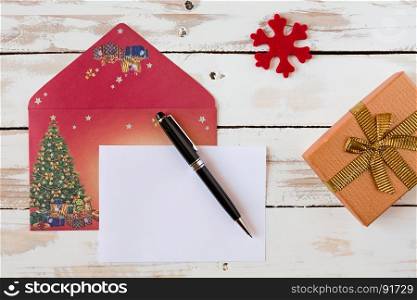 Christmas letter and pen over a rustic wooden table with present. Christmas letter over a rustic wooden table