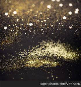 Christmas light background. Abstract glitter bokeh and scattered sparkles in gold, on black. Beautiful Christmas light background. Abstract glitter bokeh and scattered sparkles in gold, on black