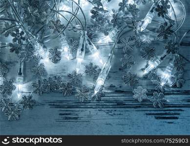 Christmas lights decoration with silver snowflakes on wooden background