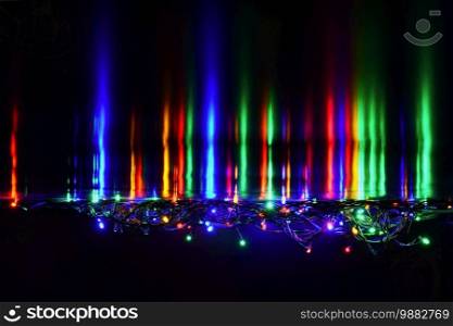 Christmas lights on black background with copy space. Colored reflecting surface.