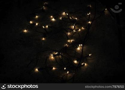 Christmas lights on dark stone black background darkness. Christmas lights on dark stone black background