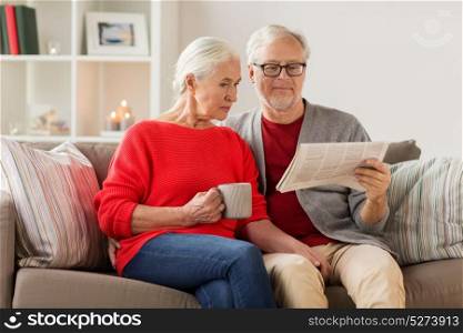 christmas, mass media and people concept - happy senior couple reading newspaper at home. happy senior couple reading newspaper at christmas