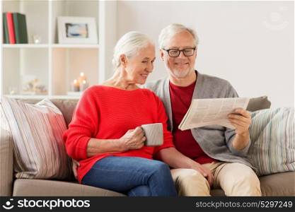 christmas, mass media and people concept - happy smiling senior couple reading newspaper at home. happy senior couple reading newspaper at christmas