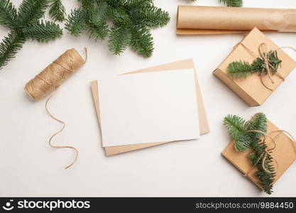 Christmas mockup greeting card with envelope on wooden white background with fir tree branches and happy new year decorations. Top view copyspace.. Christmas mockup greeting card with envelope on wooden white background with fir tree branches and happy new year decorations. Top view copyspace