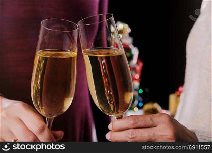 Christmas or New Year Celebration people hands with crystal glasses full of champagne near the Christmas tree and space for your text