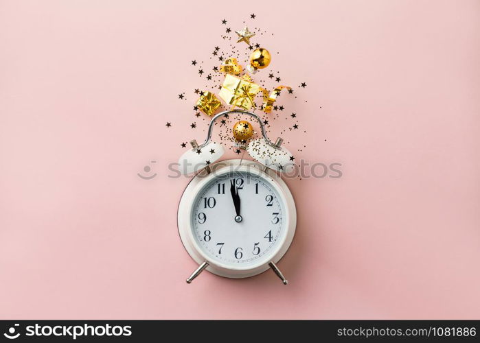 Christmas or New Year composition on pink background with retro alarm clock and Christmas decorations - stars, confetti, balls and gift boxes, top view, flat lay