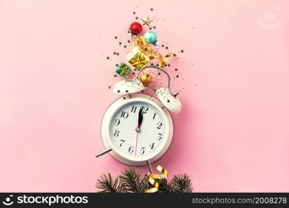 Christmas or New Year composition on pink background with retro alarm clock and Christmas decorations - stars, confetti, balls and gift boxes, top view, flat lay