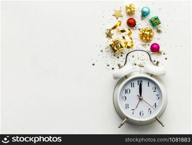 Christmas or New Year composition on white background with retro alarm clock and Christmas decorations - stars, confetti, balls and gift boxes, top view, flat lay