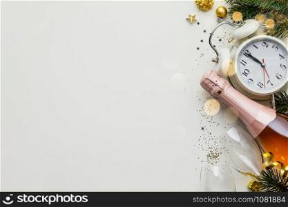 Christmas or New Year composition on white background with retro alarm clock, bottle of champagne, glasses and Christmas decorations - stars, confetti, balls and gift boxes, top view, flat lay