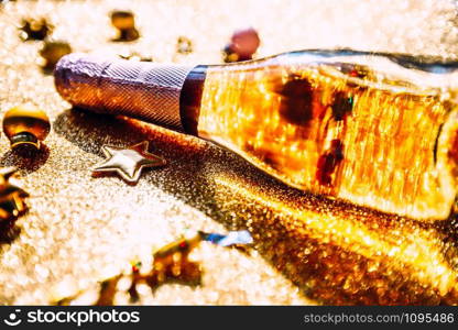 Christmas or New Year composition with bottle of rose champagne and golden sparkling decoration on golden shiny background, side view with festive bokeh and shadows. Party Celebration creative concept