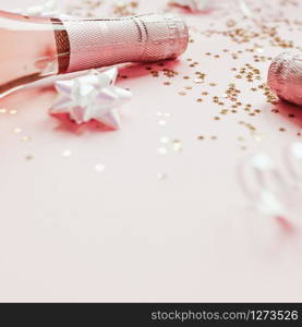 Christmas or New Year composition with bottles of rose champagne and golden shiny sparkle star confetti on pastel pink background, side view. Party Celebration creative concept