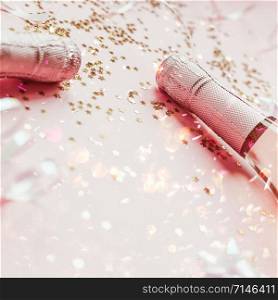 Christmas or New Year composition with bottles of rose champagne and golden shiny sparkle star confetti on pastel pink background, side view. Party Celebration creative concept