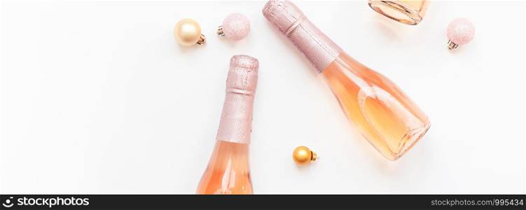 Christmas or New Year composition with bottles of rose champagne and golden shiny sparkle star confetti isolated on white background, top view. Celebration flat lay. Party creative concept