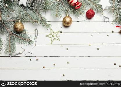 Christmas or New Year decoration background: fur-tree branches, colorful glass balls and glittering stars on white wooden background, top view, copy space. Christmas or New Year decoration background: fur-tree branches, colorful glass balls, decoration and glittering stars on white wooden background, top view, copy space.
