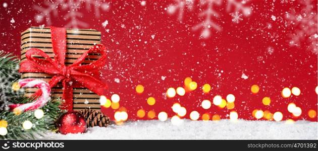 Christmas or New Year festive background. Gift box on red snowy Christmas or New Year festive background with blurred decorative lights