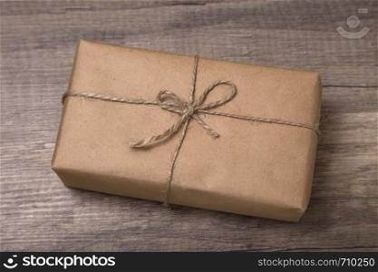Christmas or New Year gift box wrapped in kraft paper on old wooden background.