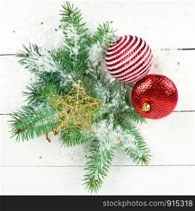 Christmas or New Year ornament. Sprigs of fir and bright decorations on a white wooden surface.