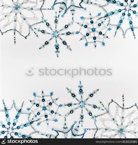 Christmas or winter concept. Frame of various handmade blue snowflakes made from beads and bugle on white desk background, top view. Layout for greeting card and winter holidays