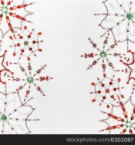 Christmas or winter concept. Frame of various handmade red green snowflakes made from beads and bugle on white desk background, top view. Layout for greeting card and winter holidays