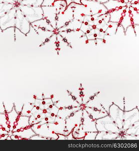 Christmas or winter concept. Frame of various handmade red snowflakes made from beads and bugle on white desk background, top view. Layout for greeting card and winter holidays
