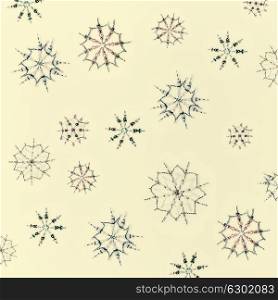 Christmas or winter concept. Pattern of various handmade snowflakes made from beads and bugle on beige background, top view
