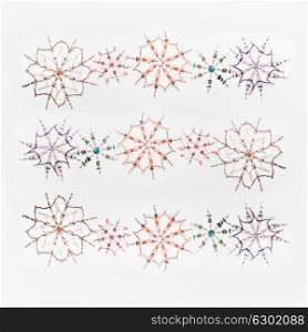 Christmas or winter concept. Pattern of various handmade snowflakes made from beads and bugle on white desk background, top view. Layout for greeting card and winter holidays