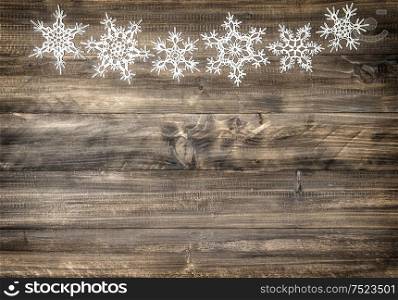 Christmas ornament white snowflakes on rustic wooden background. Holidays decoration. Vintage style toned picture