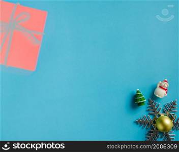 Christmas ornaments background of snowman, snowflake, christmas gold ball and fir tree on blue paper background. Flat layout with copy space design.
