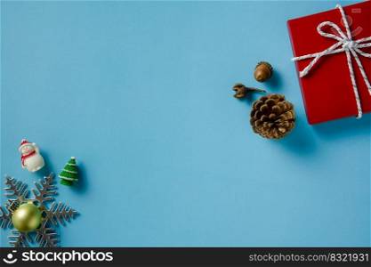 Christmas ornaments decoration of snowman, red gift box, pine cone, acorn, snowflake, christmas ball and fir tree on blue paper background. Flat layout with copy space design.