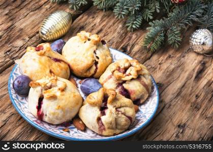 Christmas pastries with plum. Christmas sweet plum buns on the background of Christmas decorations