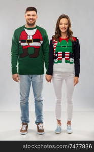 christmas, people and holidays concept - happy couple at ugly sweater party. happy couple at christmas ugly sweater party