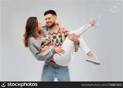christmas, people and holidays concept - happy couple at ugly sweater party. happy couple at christmas ugly sweater party
