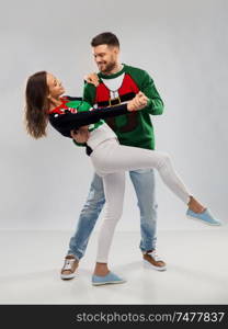 christmas, people and holidays concept - happy couple dancing at ugly sweater party. couple dancing at christmas ugly sweater party