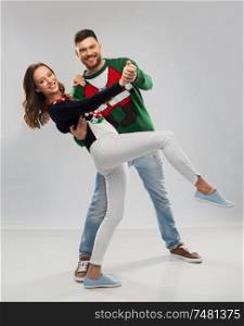 christmas, people and holidays concept - happy couple dancing at ugly sweater party. couple dancing at christmas ugly sweater party