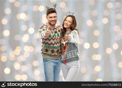 christmas, people and holidays concept - happy couple hugging at ugly sweater party over festive lights background. happy couple at christmas ugly sweater party