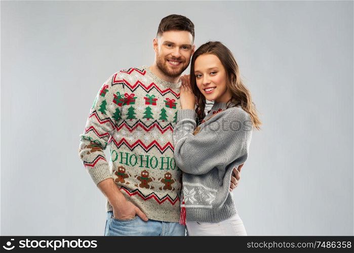christmas, people and holidays concept - portrait of happy couple at ugly sweater party. happy couple at christmas ugly sweater party