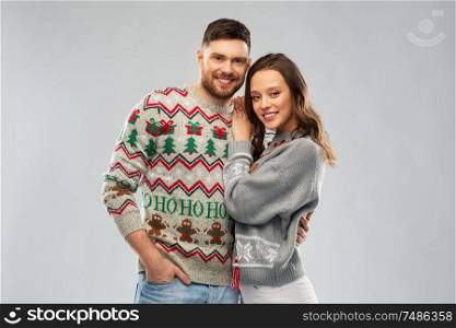 christmas, people and holidays concept - portrait of happy couple at ugly sweater party. happy couple at christmas ugly sweater party