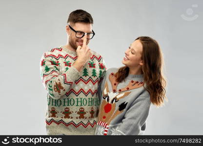 christmas, people and holidays concept - portrait of happy couple at ugly sweater party. happy couple at christmas ugly sweater party