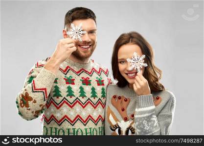 christmas, people and holidays concept - portrait of happy couple at ugly sweater party with snowflakes. happy couple at christmas ugly sweater party