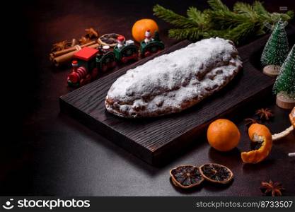 Christmas pie stollen with marzipan, berries and nuts on a dark concrete background. Preparation of the festive table. Christmas pie stollen with marzipan, berries and nuts on a dark concrete background