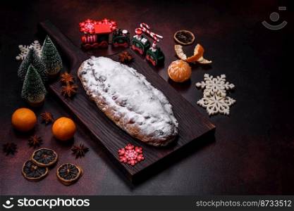 Christmas pie stollen with marzipan, berries and nuts on a dark concrete background. Preparation of the festive table. Christmas pie stollen with marzipan, berries and nuts on a dark concrete background