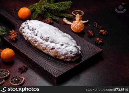 Christmas pie stollen with marzipan, berries and nuts on a dark concrete background. Preparation of the festive table. Christmas pie stollen with marzipan, berries and nuts on a dark concrete background