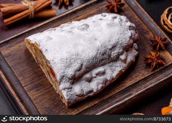 Christmas pie stollen with marzipan, berries and nuts on a dark concrete background. Preparation of the festive table. Christmas pie stollen with marzipan, berries and nuts on a dark concrete background